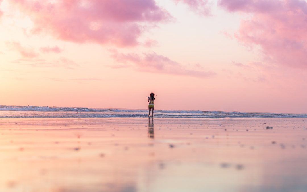 woman standing on seashore in front of body of water