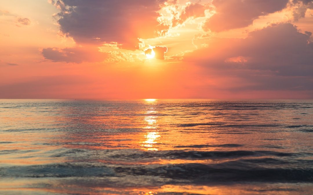 sea under white clouds at golden hour