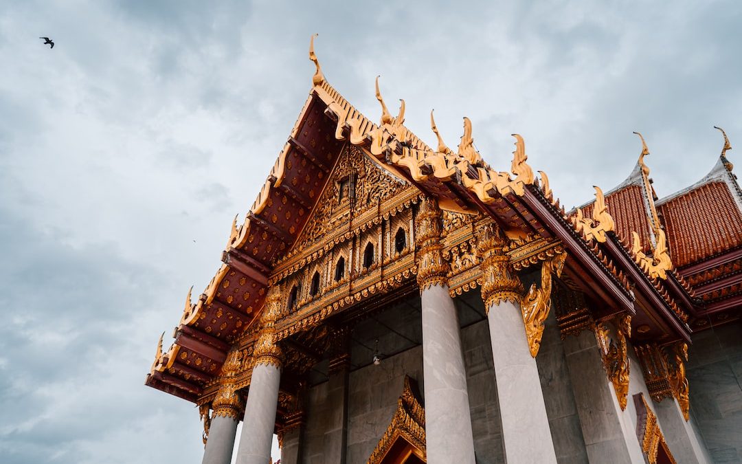 a tall building with many pillars and a bird flying in the sky