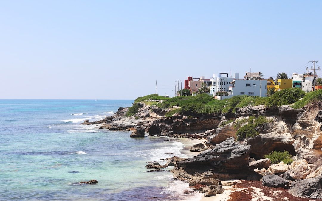 a view of a beach with houses on the cliff