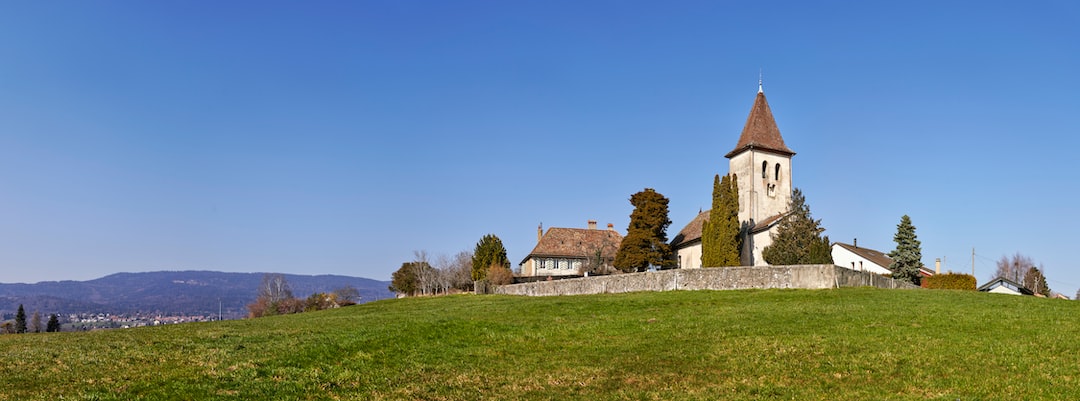 brown and white concrete house near green grass field under blue sky during daytime