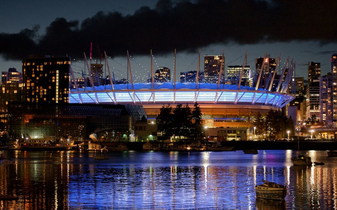 a large stadium lit up at night with a boat in the water