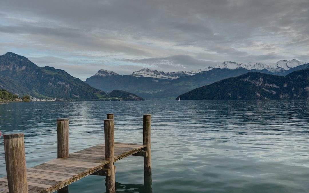 closeup photo of brown wooden dock facing mountain and calm body of water