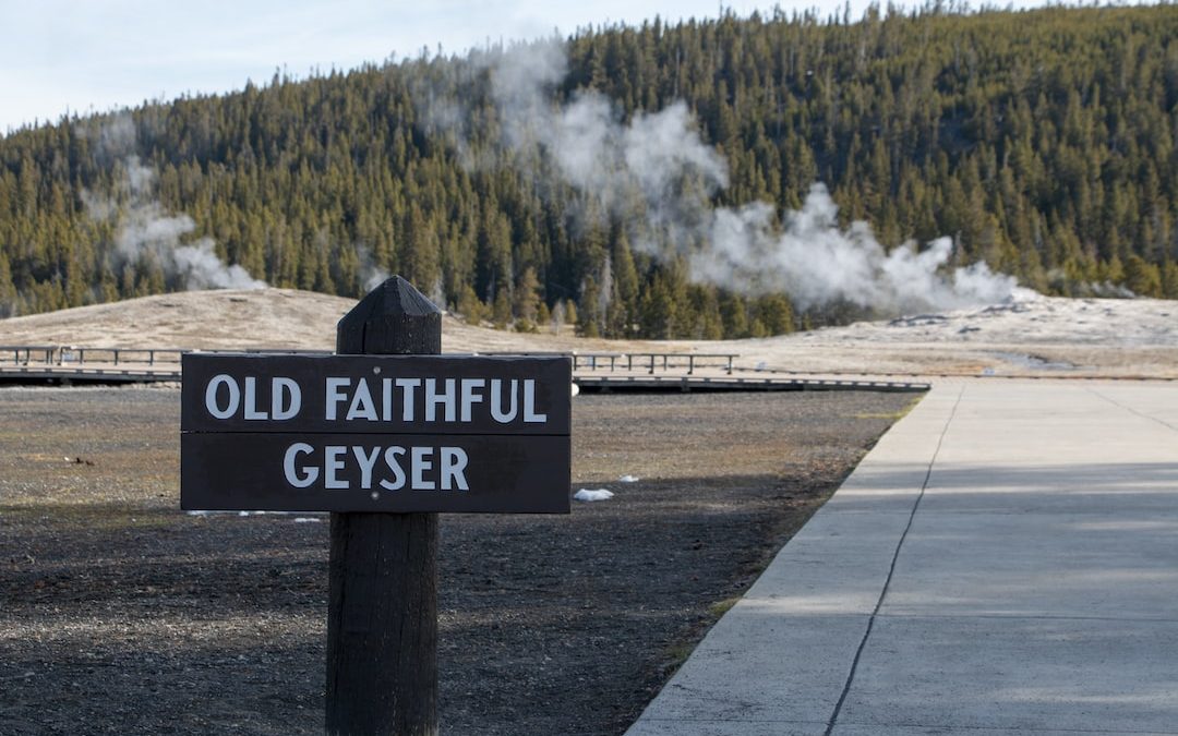 a sign on the side of a road with a large waterfall in the background