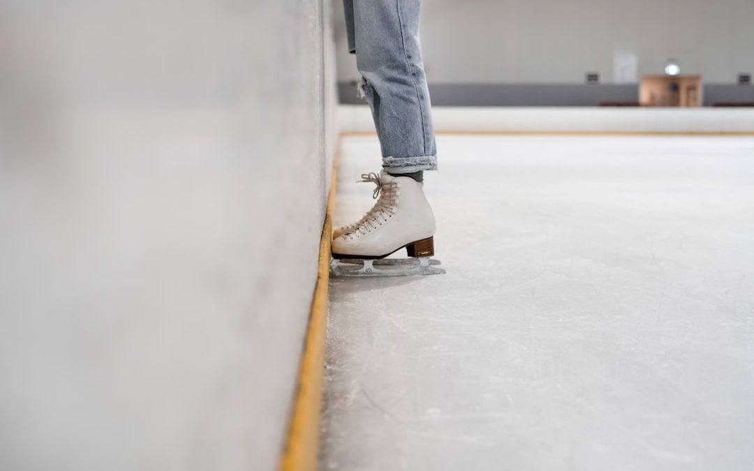 person wearing white and gray skate shoes inside ice skating rink
